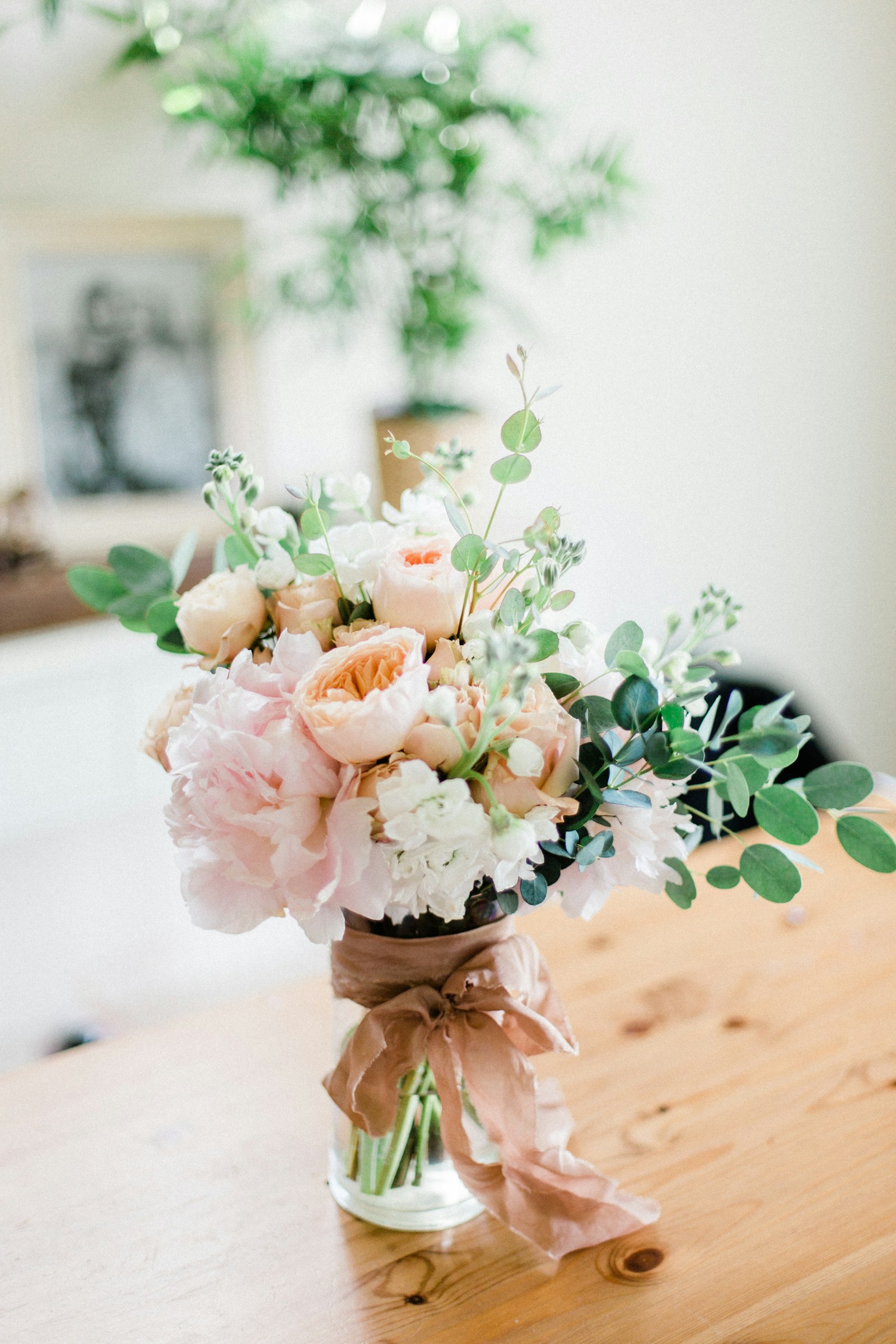 Peach and blush roses with white blooms and eucalyptus in a hand-tied bouquet